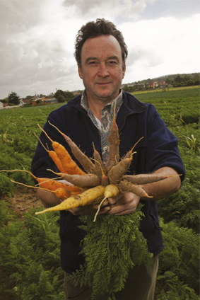 Photo d'un producteur portant une botte de carottes dans son champ