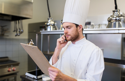 Photo présentant un chef passant commande au téléphone son menu à la main