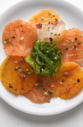 Photo d'un carpaccio de saumon aux algues vertes et baies roses, sur une assiette blanche